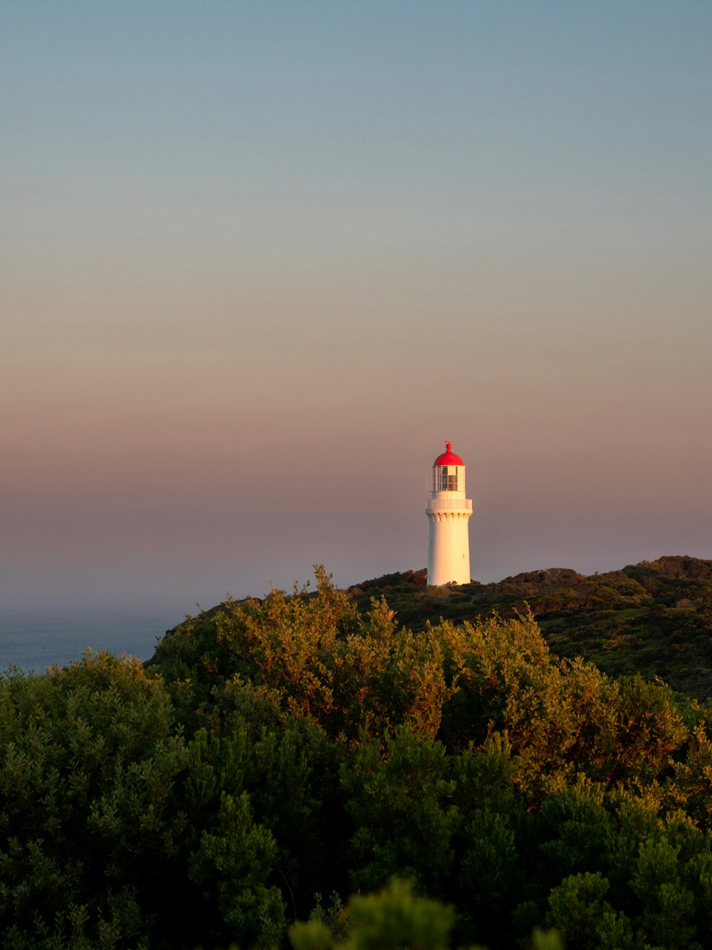 a white and red light house on top of a hill