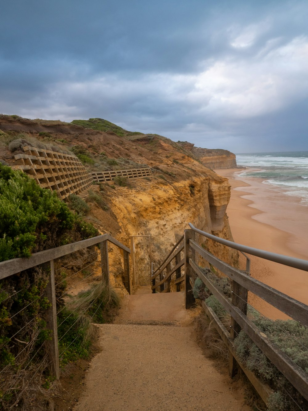a stairway leading to the beach with a cliff in the background