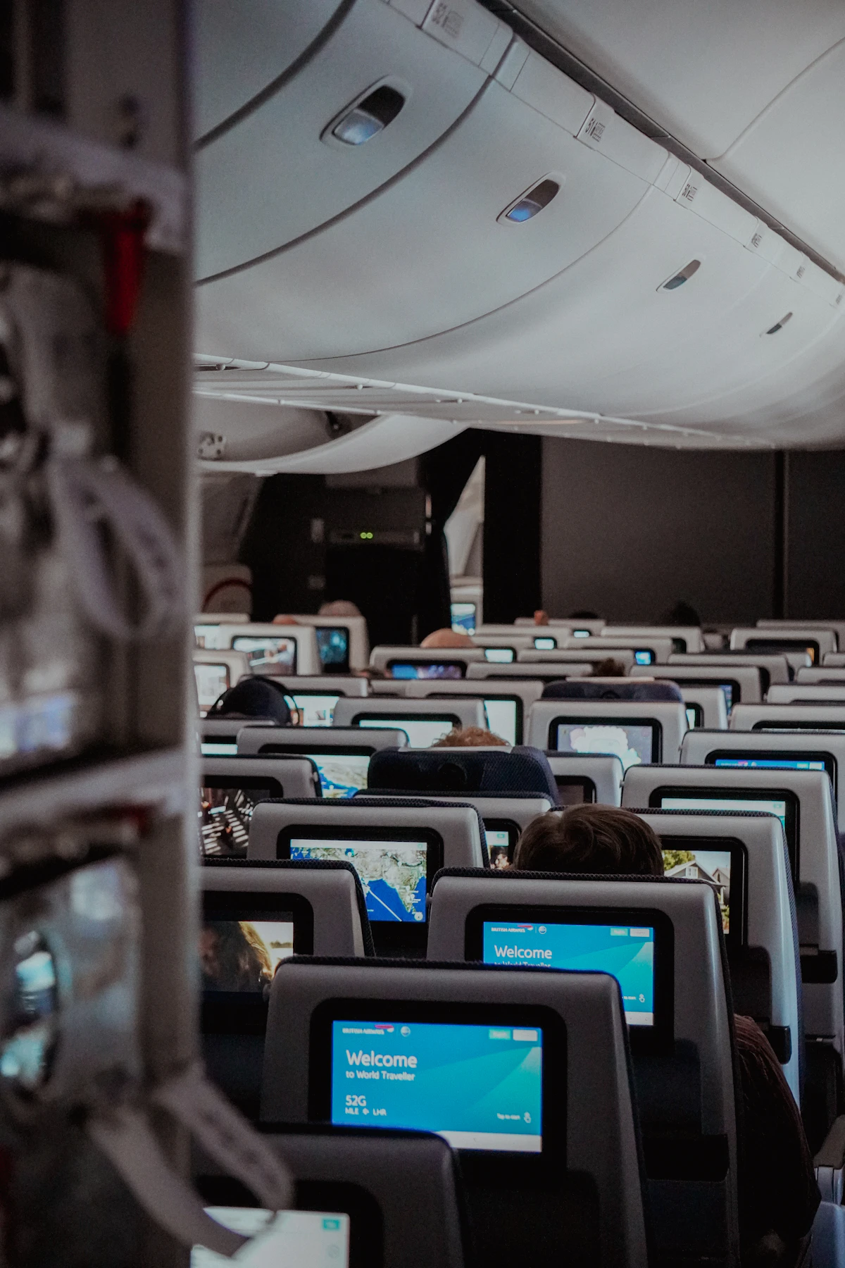 Rows of airplane seats with passengers using laptops