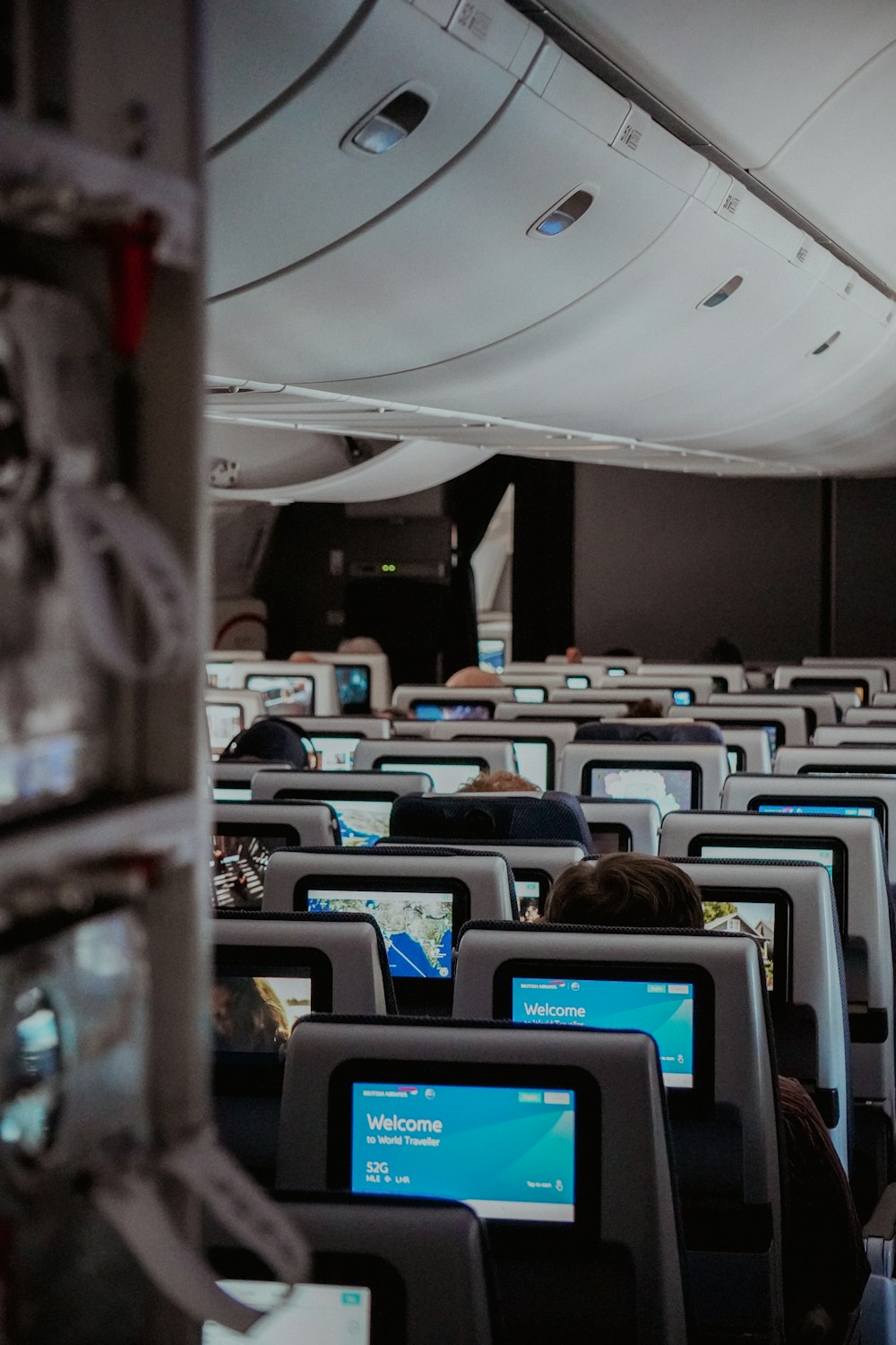 rows of seats in an airplane with computers on them
