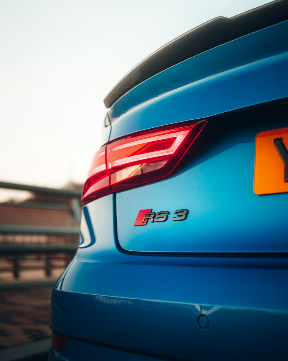 the rear end of a blue car with a yellow license plate