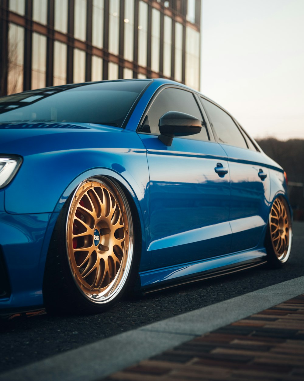 a blue car parked in front of a tall building