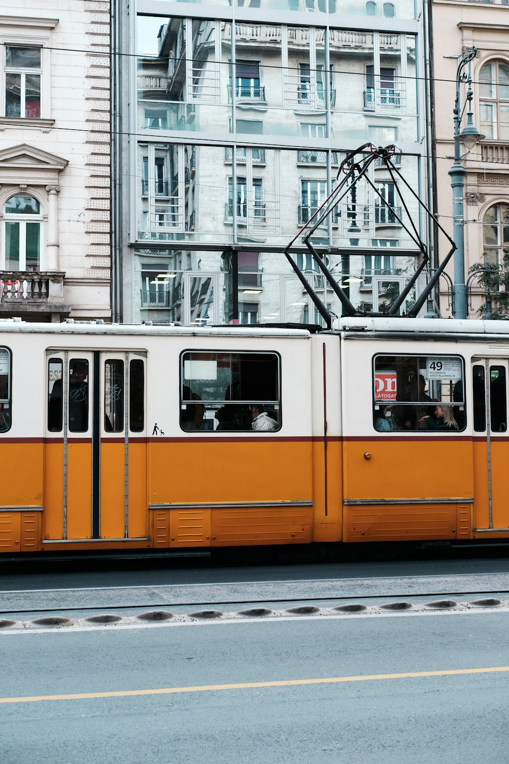 a yellow and white train traveling past tall buildings