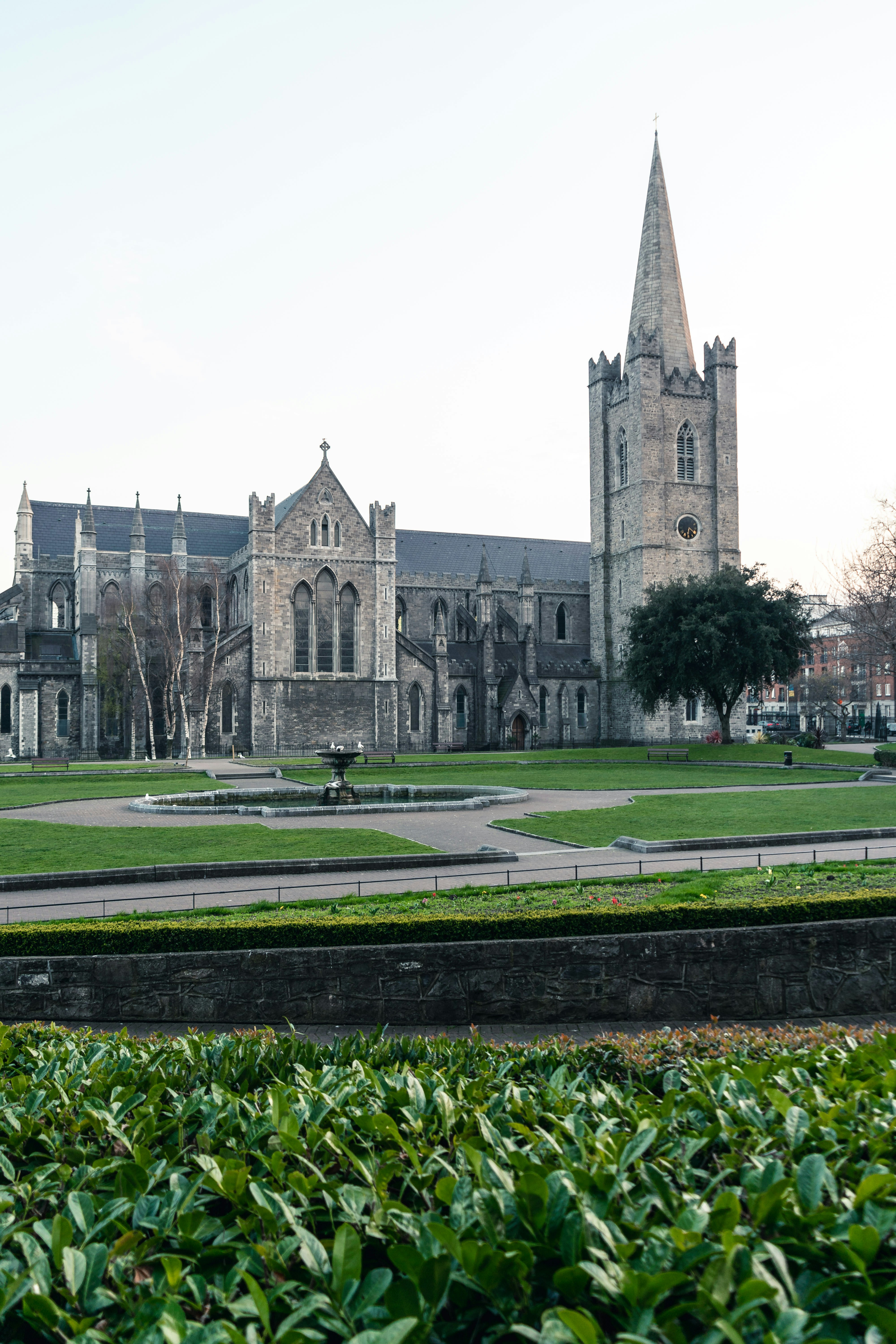 a large building with a clock tower next to a lush green park