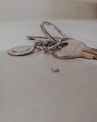 A close-up of a set of keys lying on a light-colored surface, including a silver keyring and various metal keys.