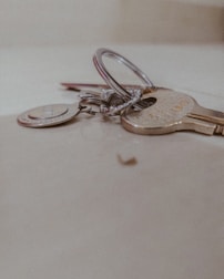 A close-up of a set of keys lying on a light-colored surface, including a silver keyring and various metal keys.