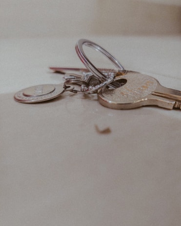 Close-up image of shiny new keys resting on a wooden table with the Quick Smith Locksmith logo in the background.