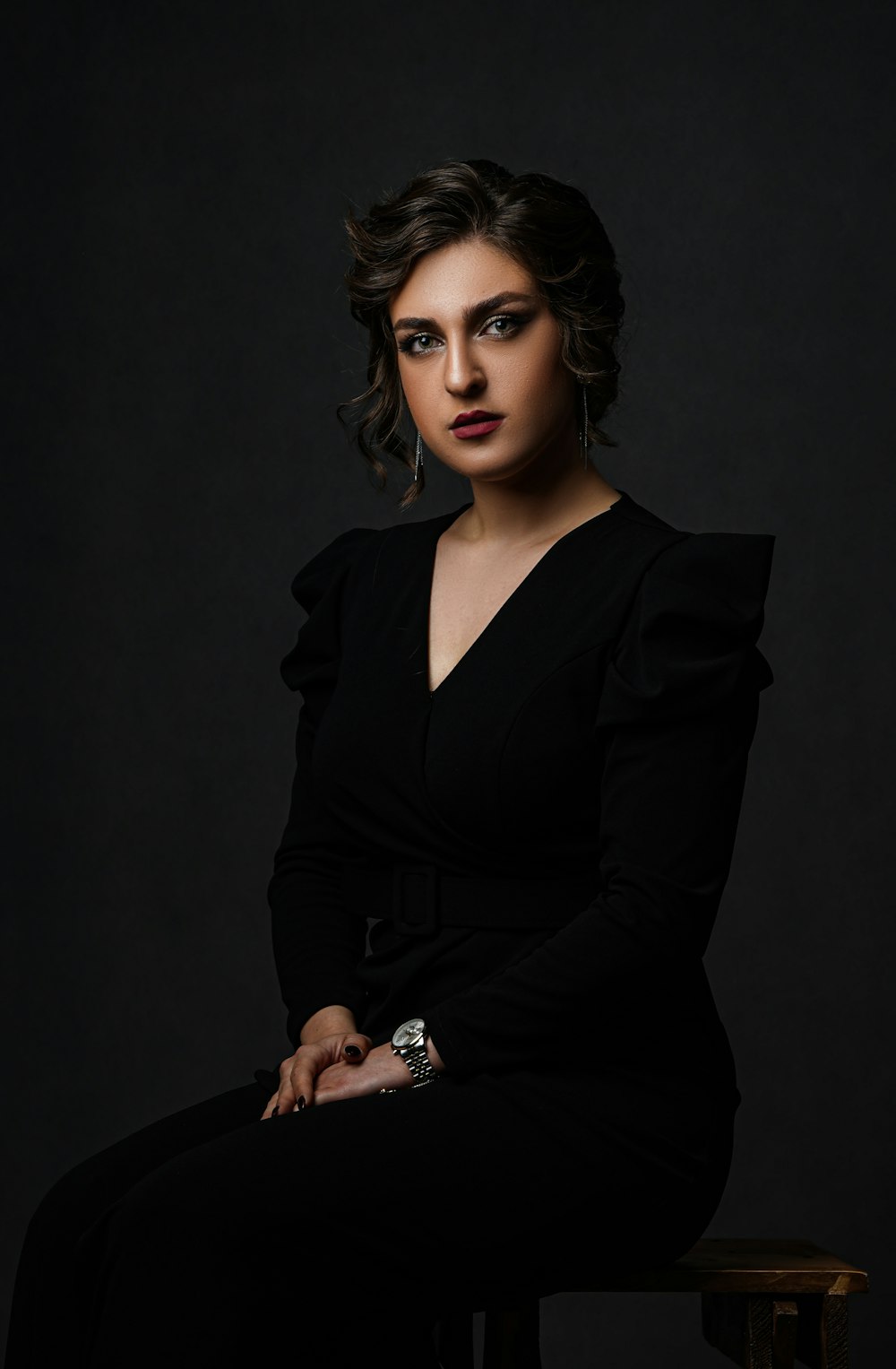 a woman in a black dress sitting on a stool