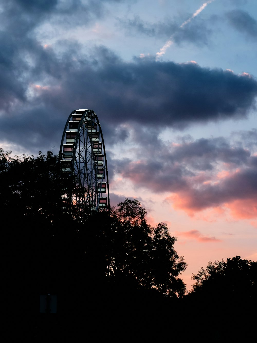 a ferris wheel is silhouetted against a cloudy sky