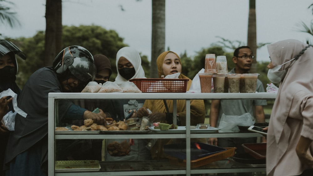 a group of people standing around a food cart