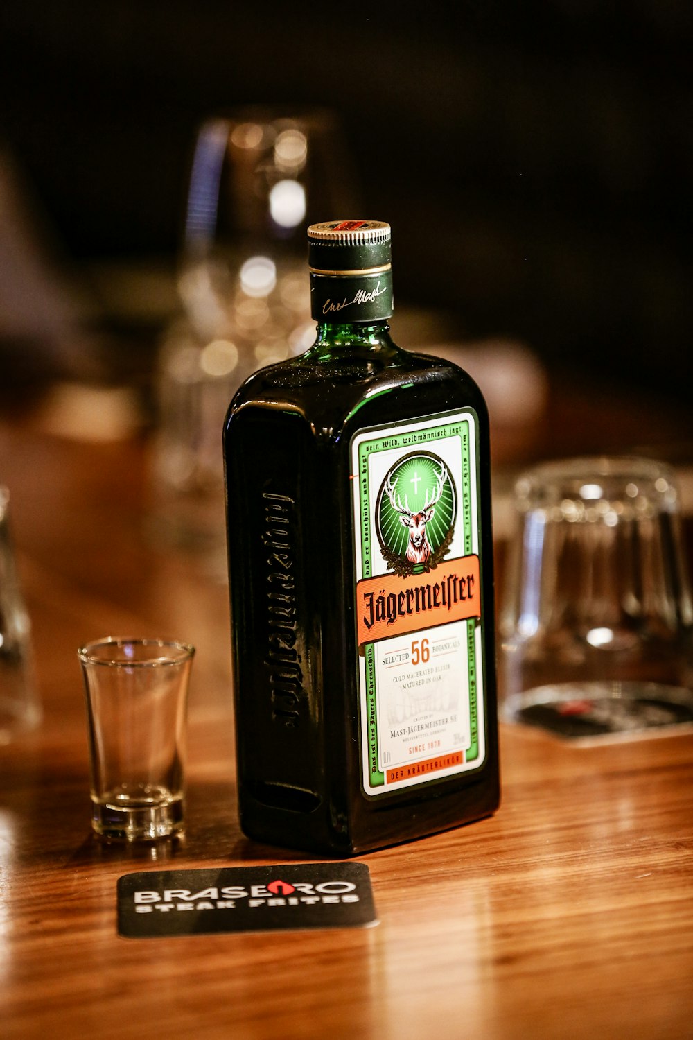 Una bottiglia di Jagermeister seduta su un tavolo accanto a un bicchierino