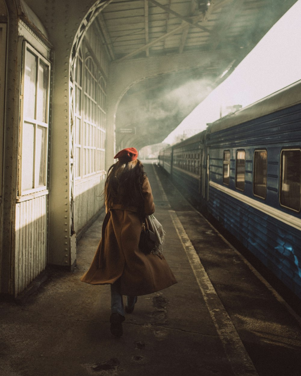 a woman walking down a train station next to a train