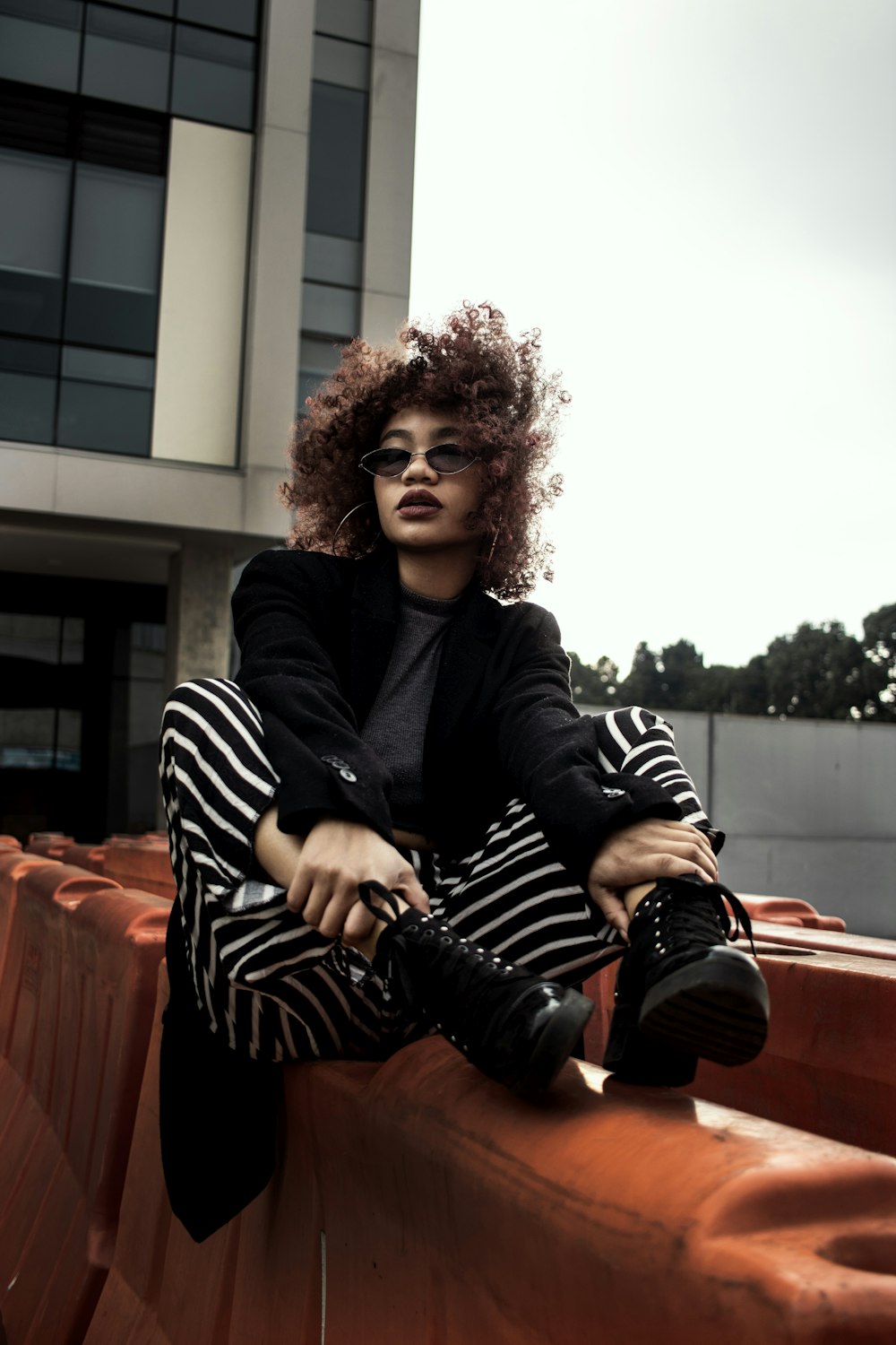 a woman with curly hair sitting on a wall