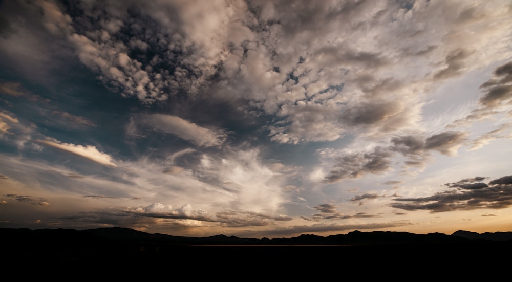 the sky is full of clouds as the sun sets