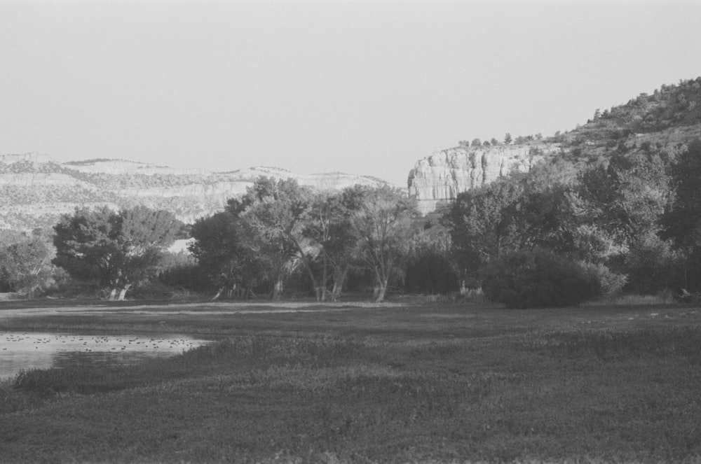 a black and white photo of a river and mountains