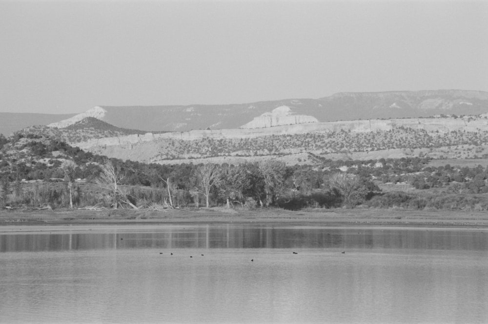 a black and white photo of a lake with mountains in the background