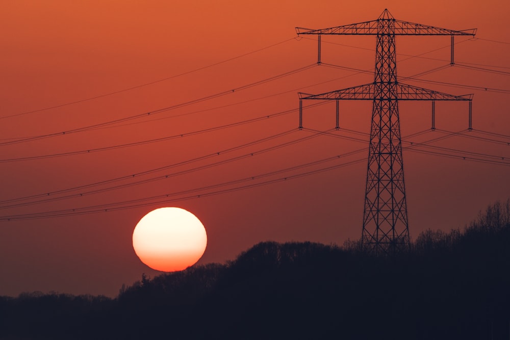 the sun is setting behind the power lines