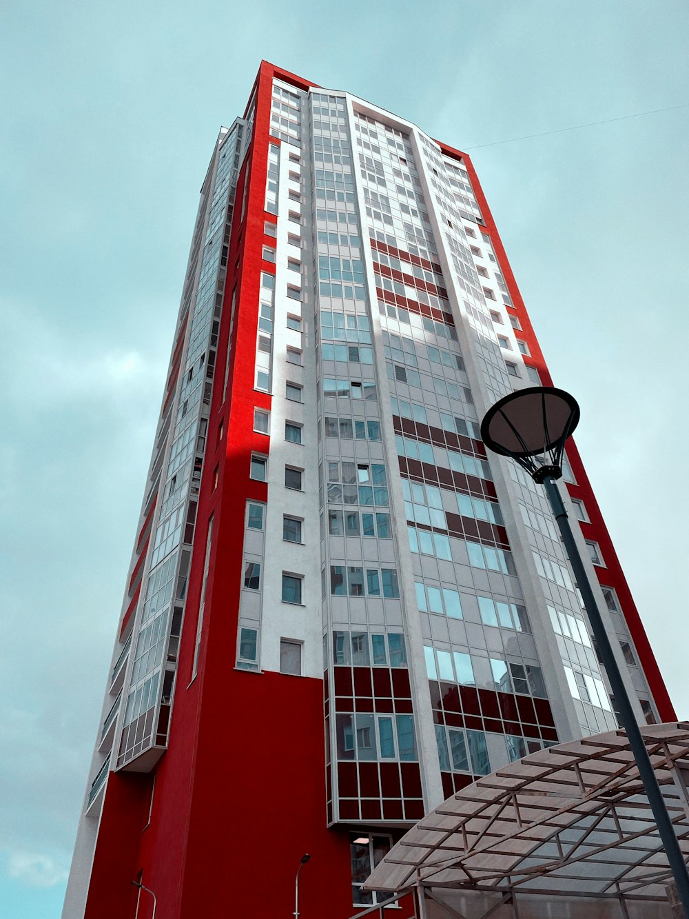 a tall red and white building next to a street light