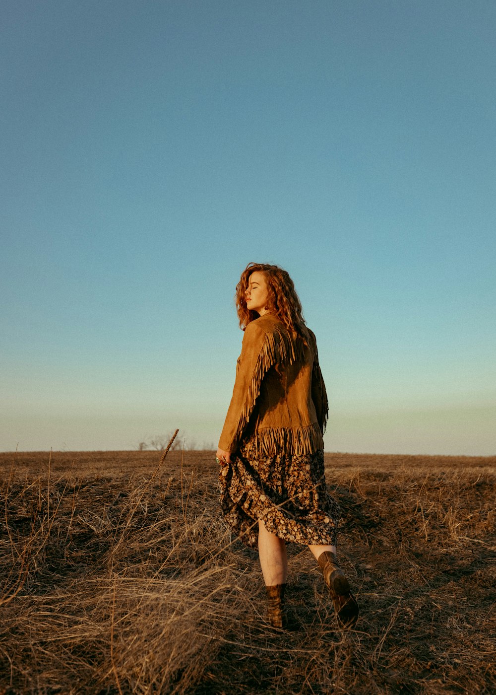 a woman walking through a dry grass field