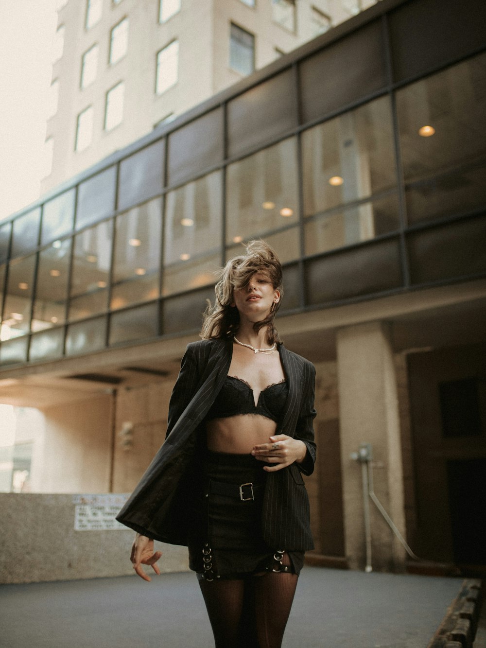 a woman in a short skirt and jacket standing in front of a building