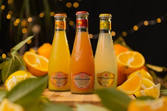 three bottles of orange juice sitting on top of a wooden table