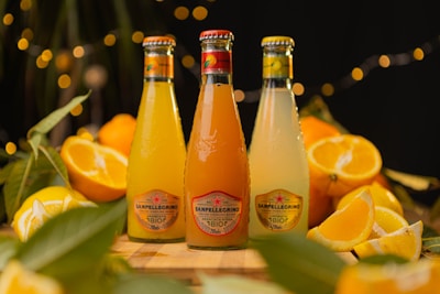 three bottles of orange juice sitting on top of a wooden table