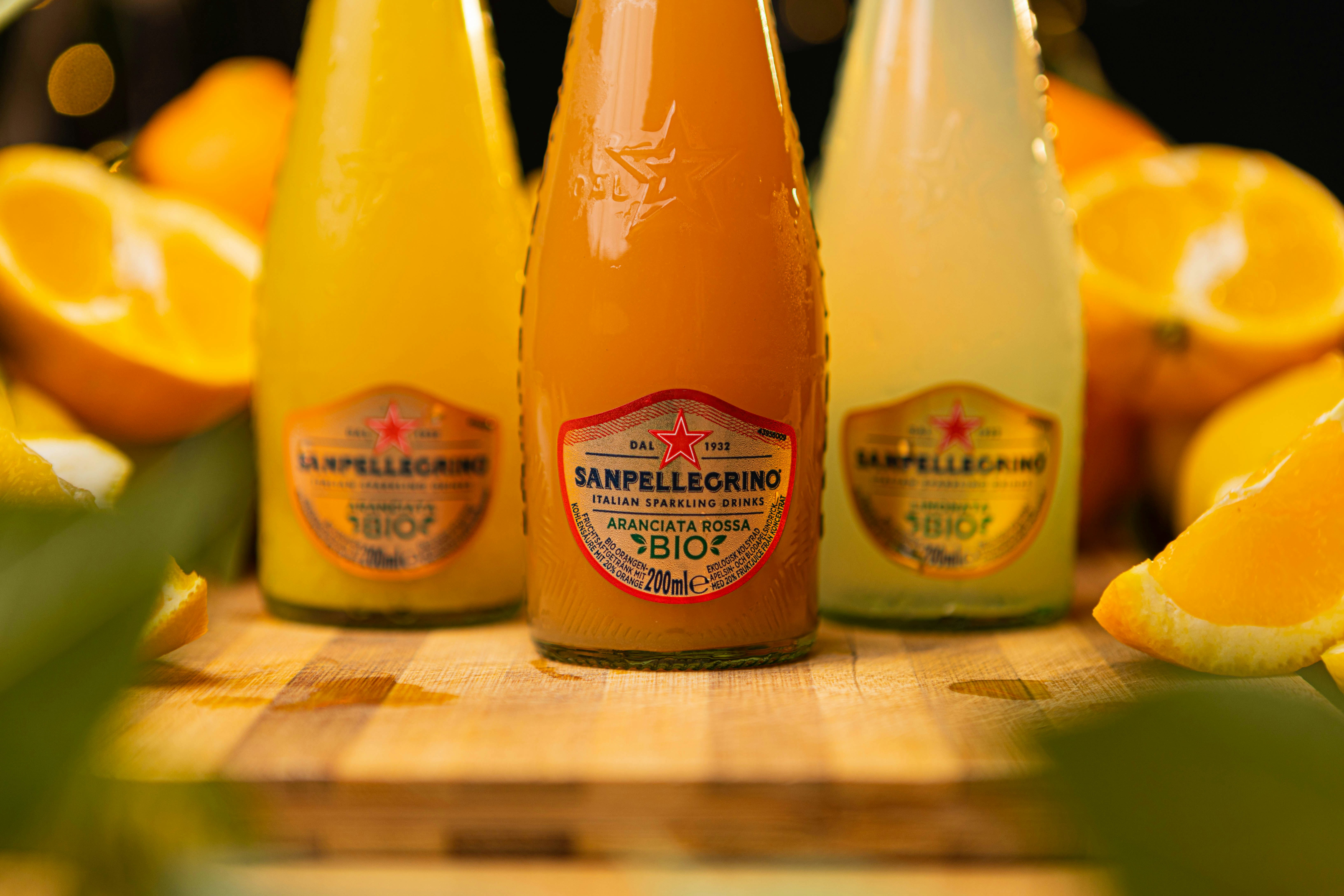 three bottles of orange juice sitting on a cutting board
