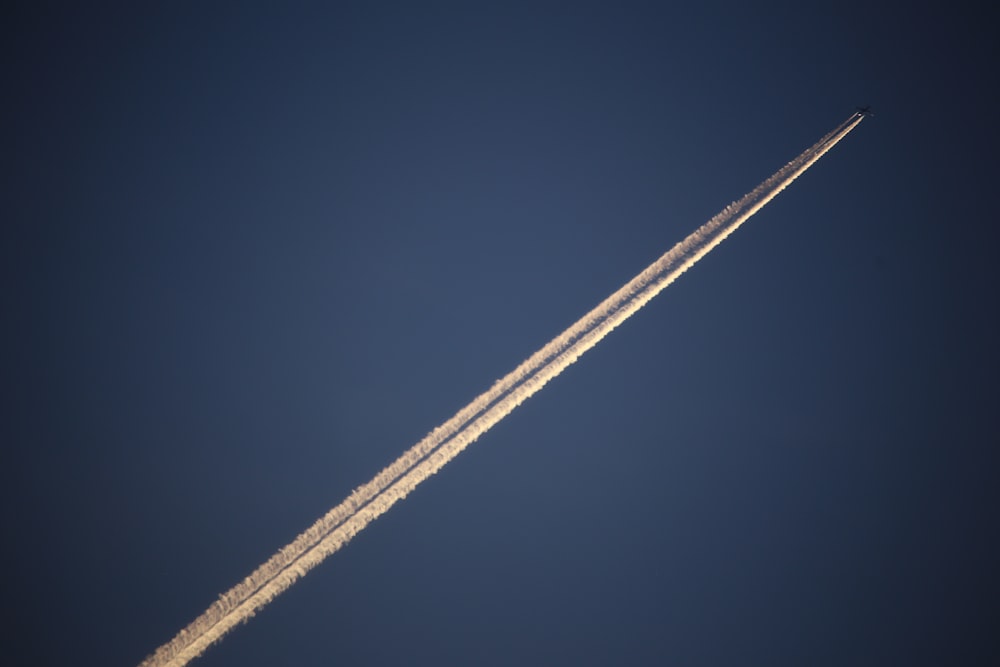 Un jet volando a través de un cielo azul con una estela