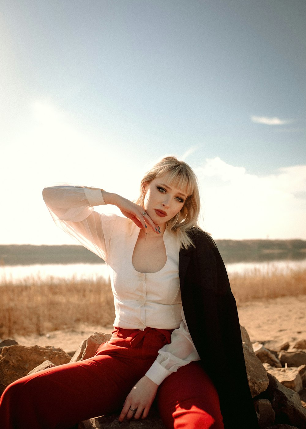 a woman sitting on top of a rock next to a body of water