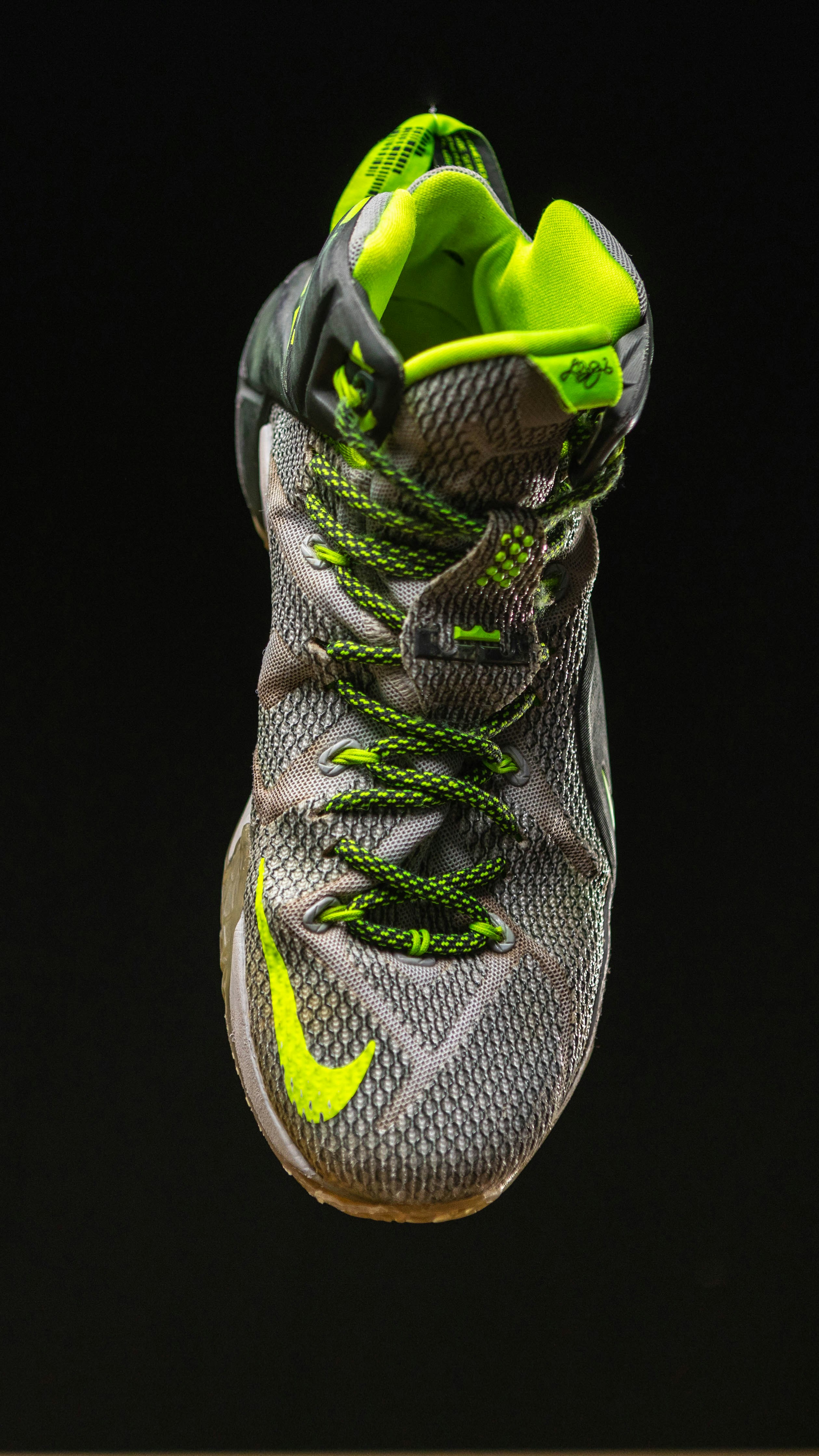 Black and neon green running shoe on track surface, dynamic angle, athletic photography