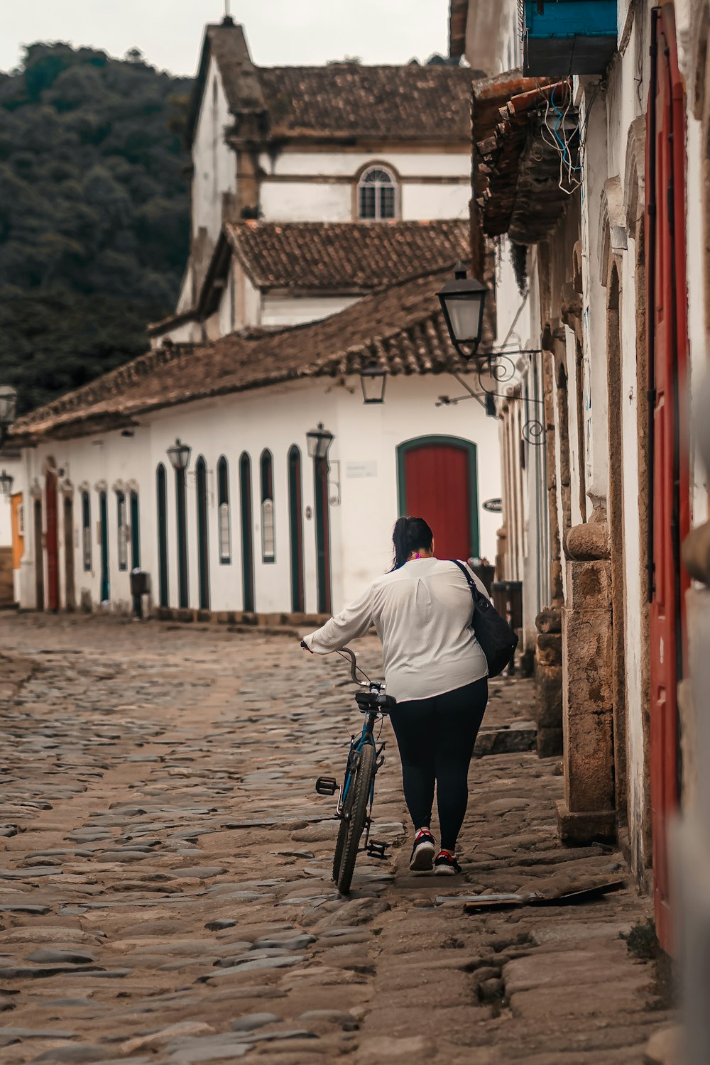 Une femme marchant à vélo dans une rue pavée