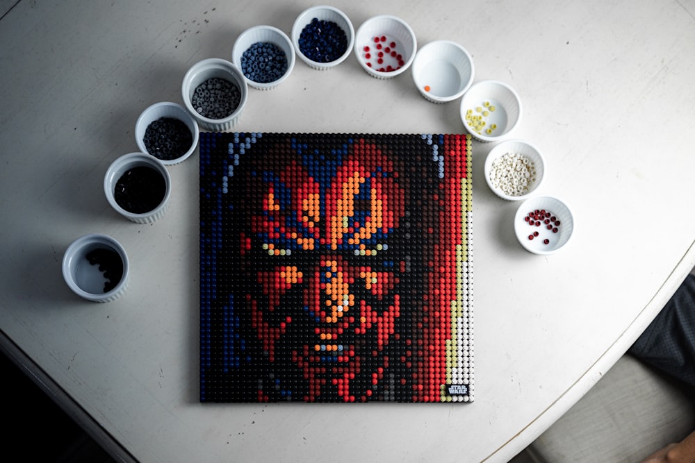 a painting of a man with a red face surrounded by bowls of black and white