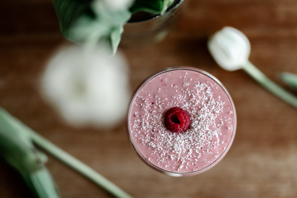 a pink drink with a raspberry in it