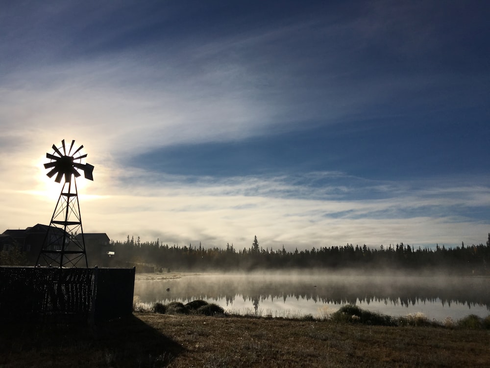 a windmill sitting on top of a dry grass field