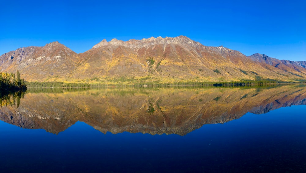 a mountain range is reflected in the still water of a lake