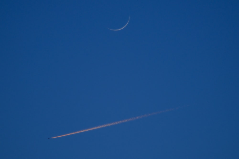 a plane flying in the sky with a crescent in the background