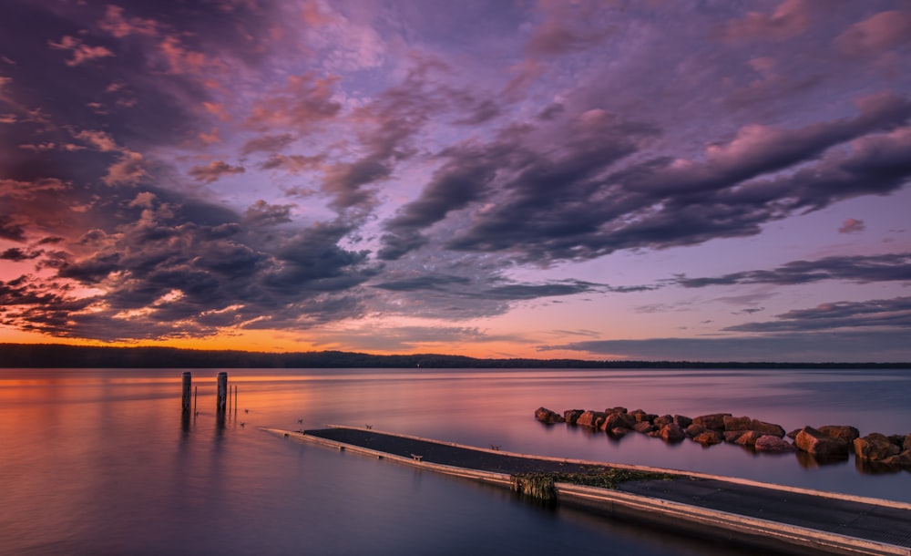 a pier sitting on top of a lake under a cloudy sky