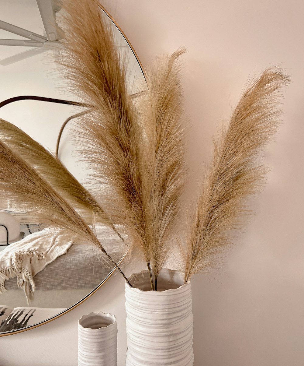 a mirror and a vase with dried grass in it