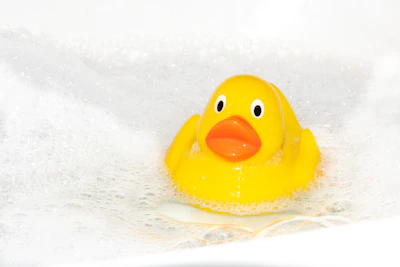 A cozy bathtub scene featuring a duck with blue polka dots floating near the faucet.