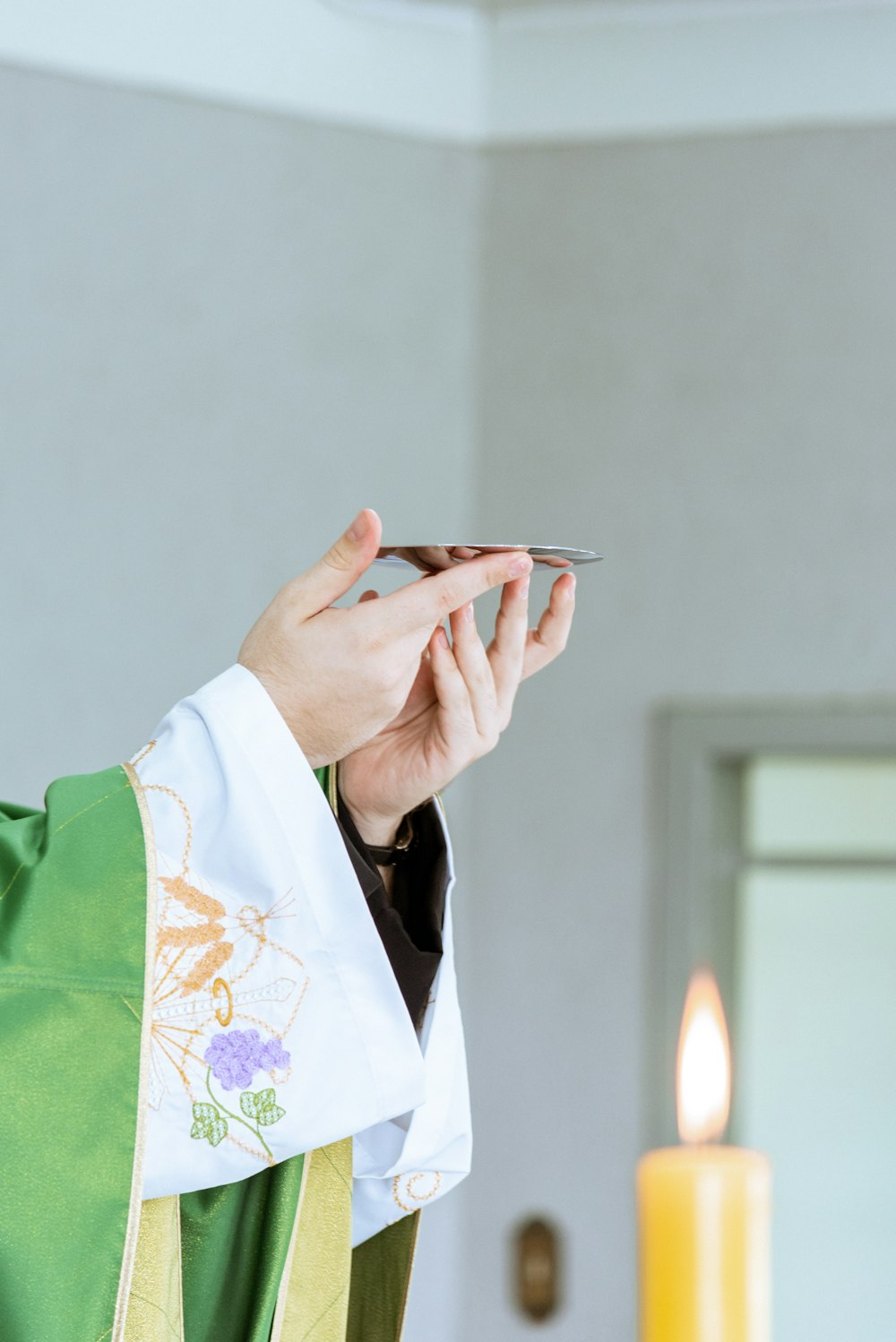 Una persona con una túnica de sacerdote sosteniendo un teléfono celular