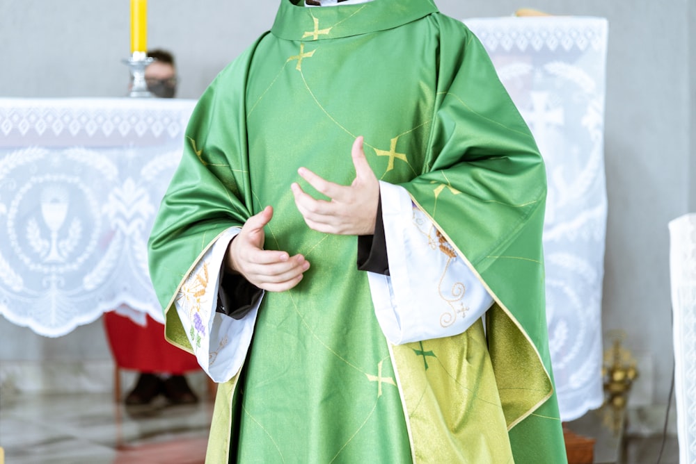 a man in a priest's outfit standing in front of a cross