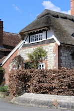 a house with a thatched roof and a hedge