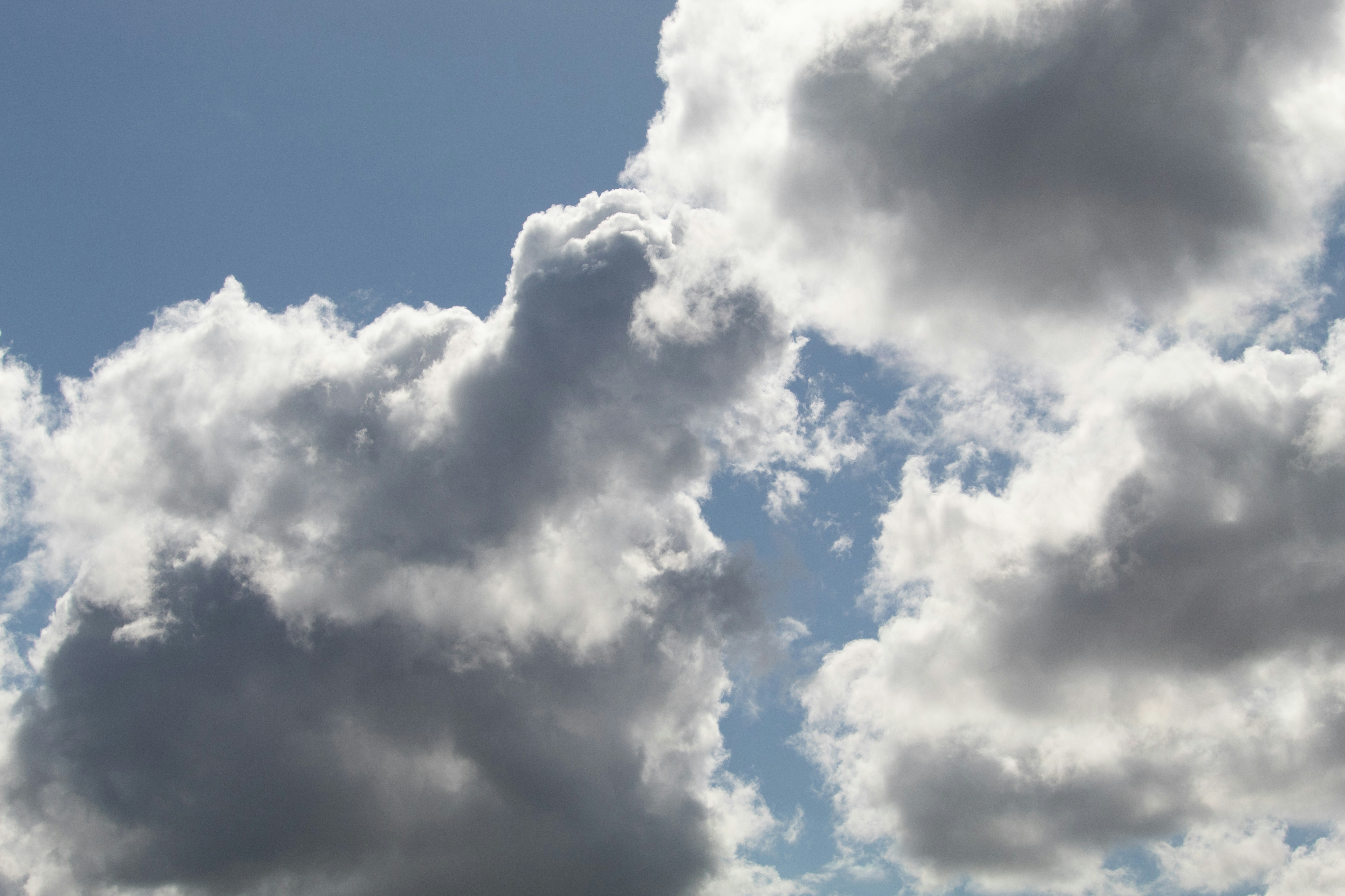 a plane flying through a cloudy blue sky