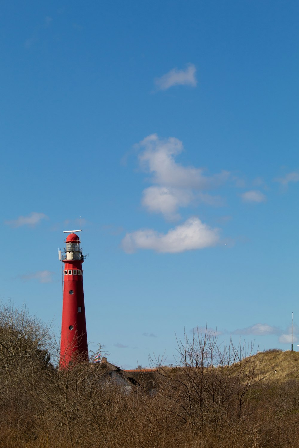 a red light house sitting on top of a hill