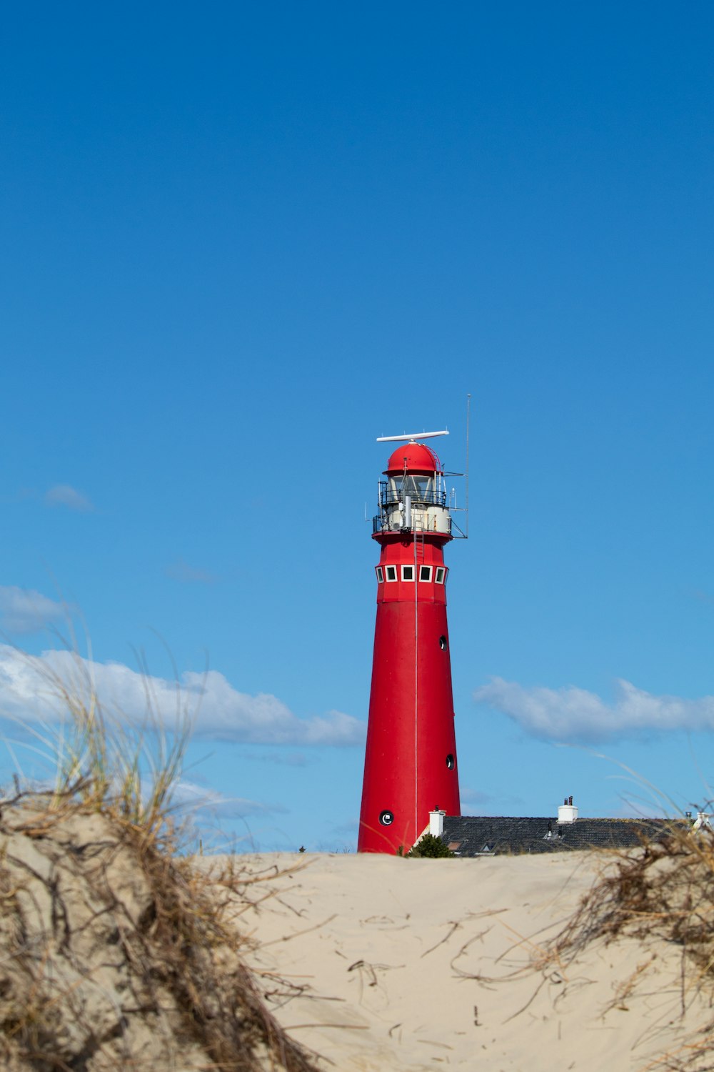 Une maison rouge assise au sommet d’une plage de sable