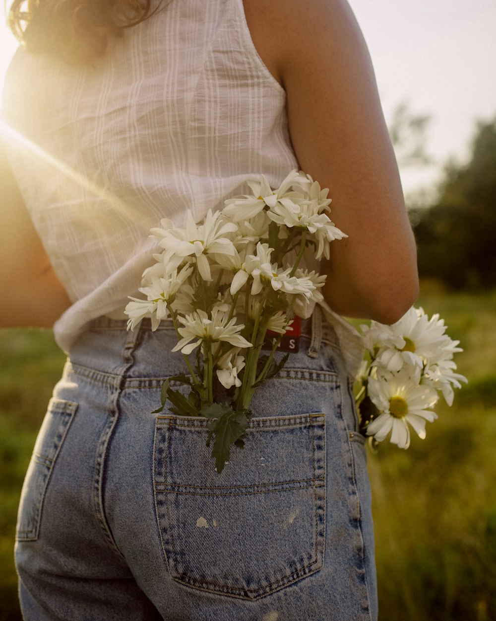 a woman holding a bouquet of daisies in her back pocket