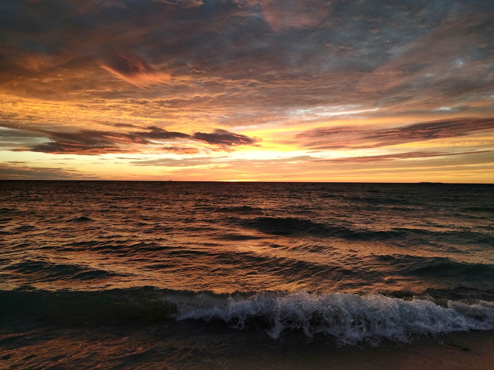 a sunset over a body of water with waves