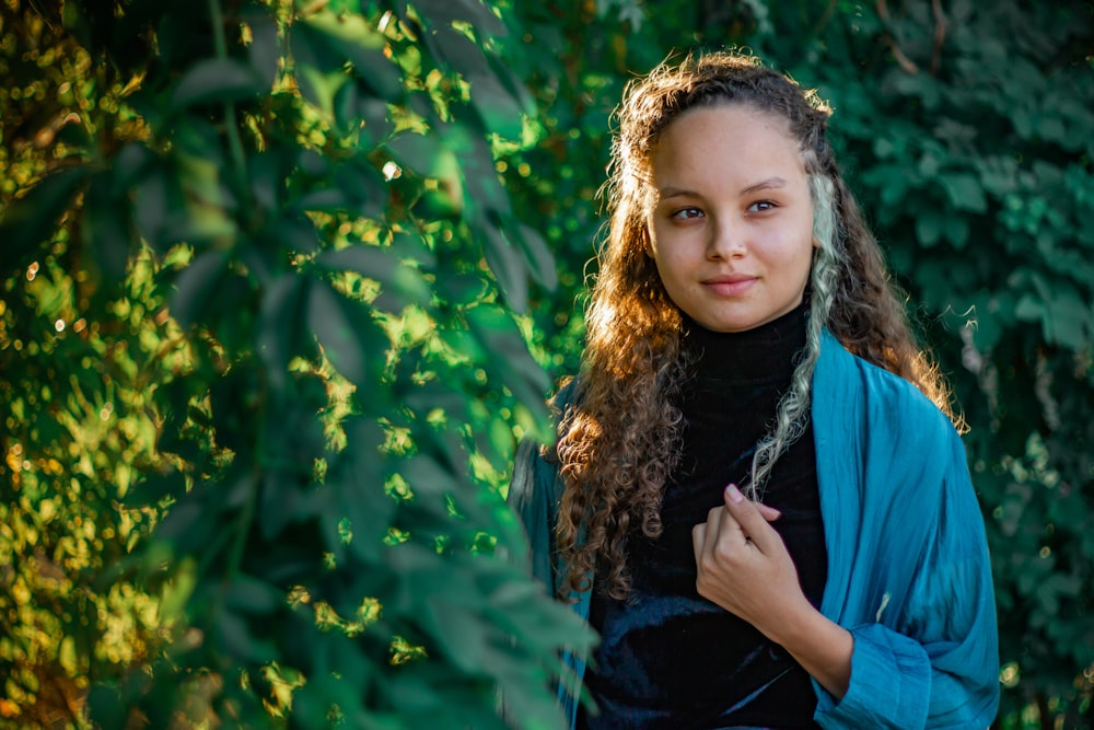 a young girl standing in front of a bush