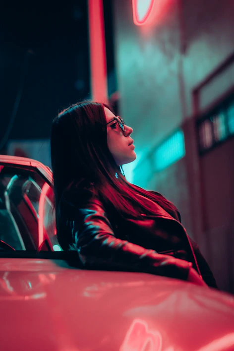 Close-up of a sleek black leather jacket with chrome zippers reflecting city lights at night.