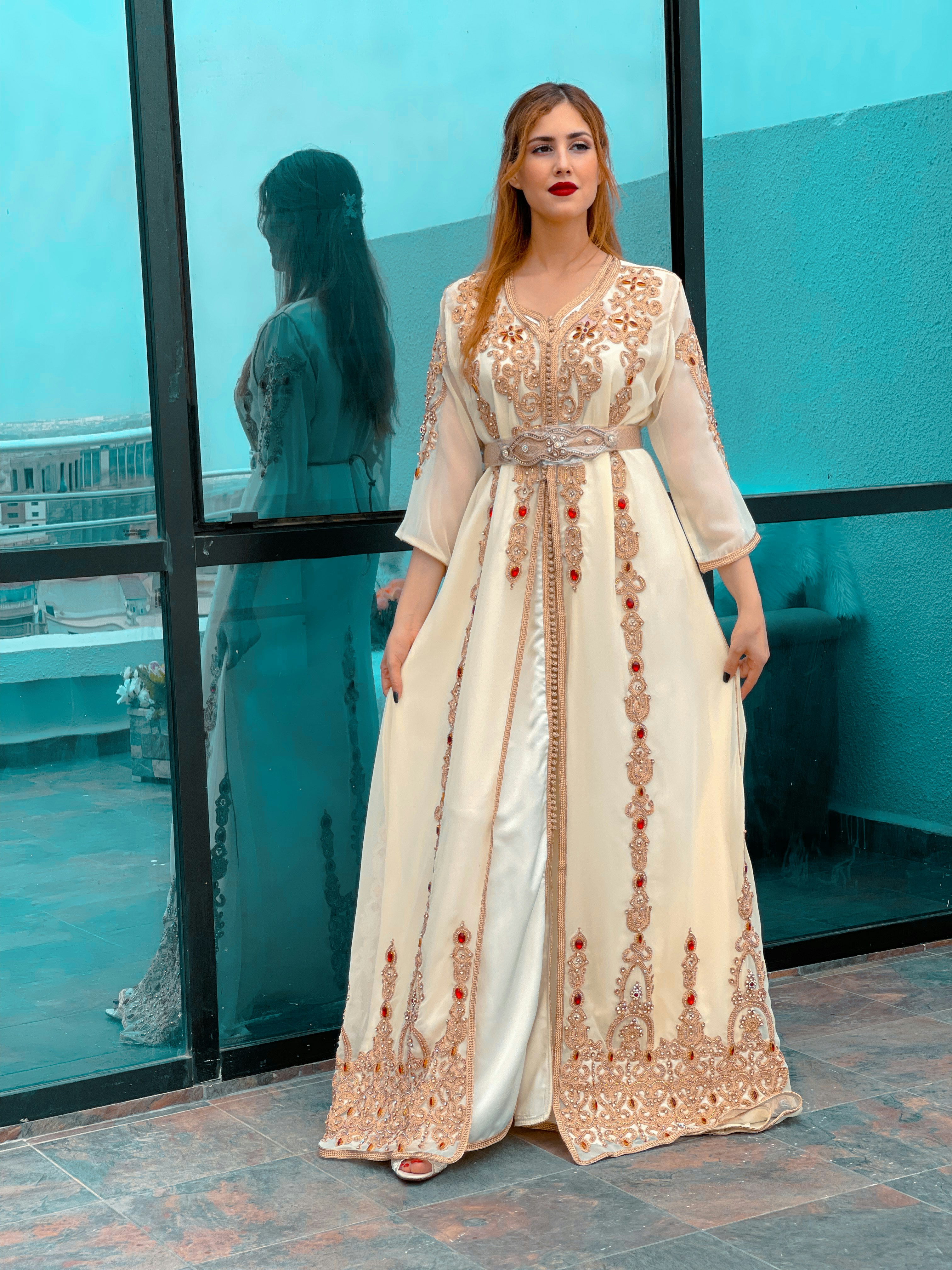 a woman standing in front of a window wearing a long dress